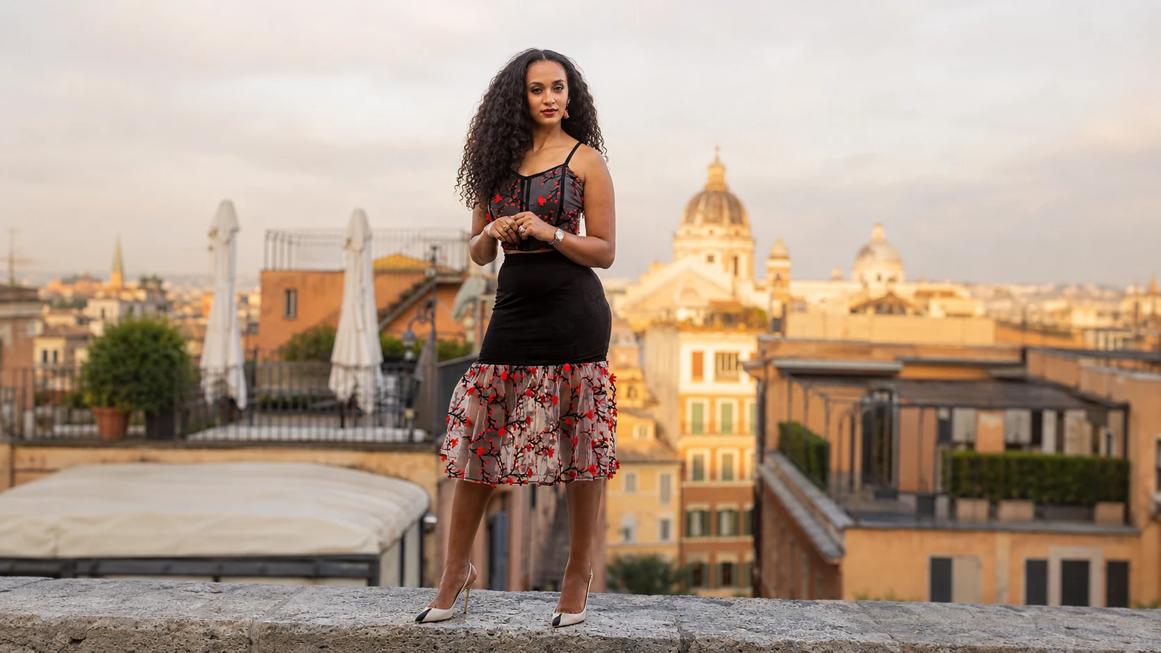 Model wearing the Scarlet Romance two-piece design above a sunlit rooftop skyline